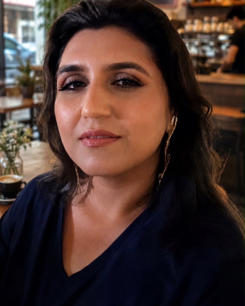 Shagufta Patel, smiling, in a café with a cup of chai